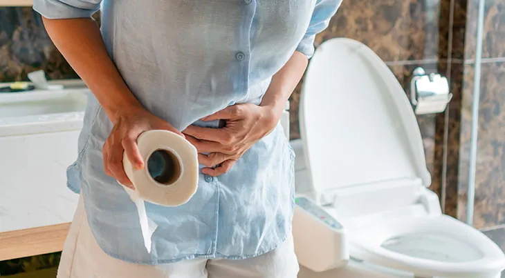 Person holding a toilet roll with a hand on their stomach