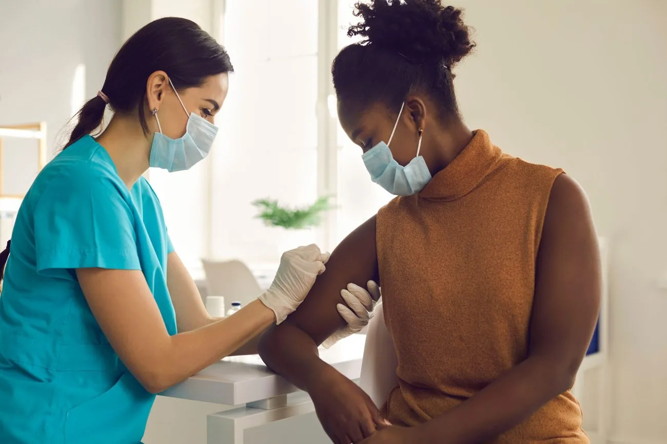 Clinician giving a vaccination into a patient’s upper arm