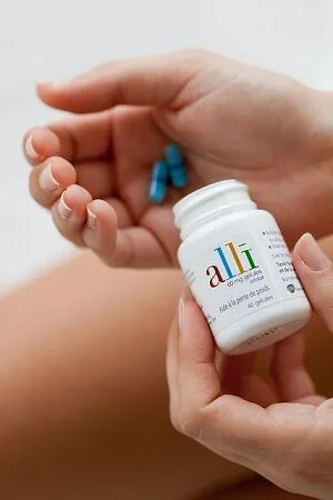 Bottle of Alli orlistat 60mg capsules held in one hand