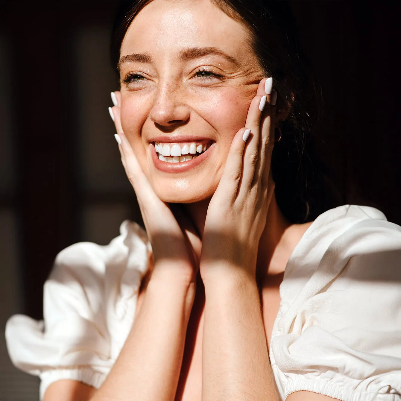 Woman smiling with her hands to her face